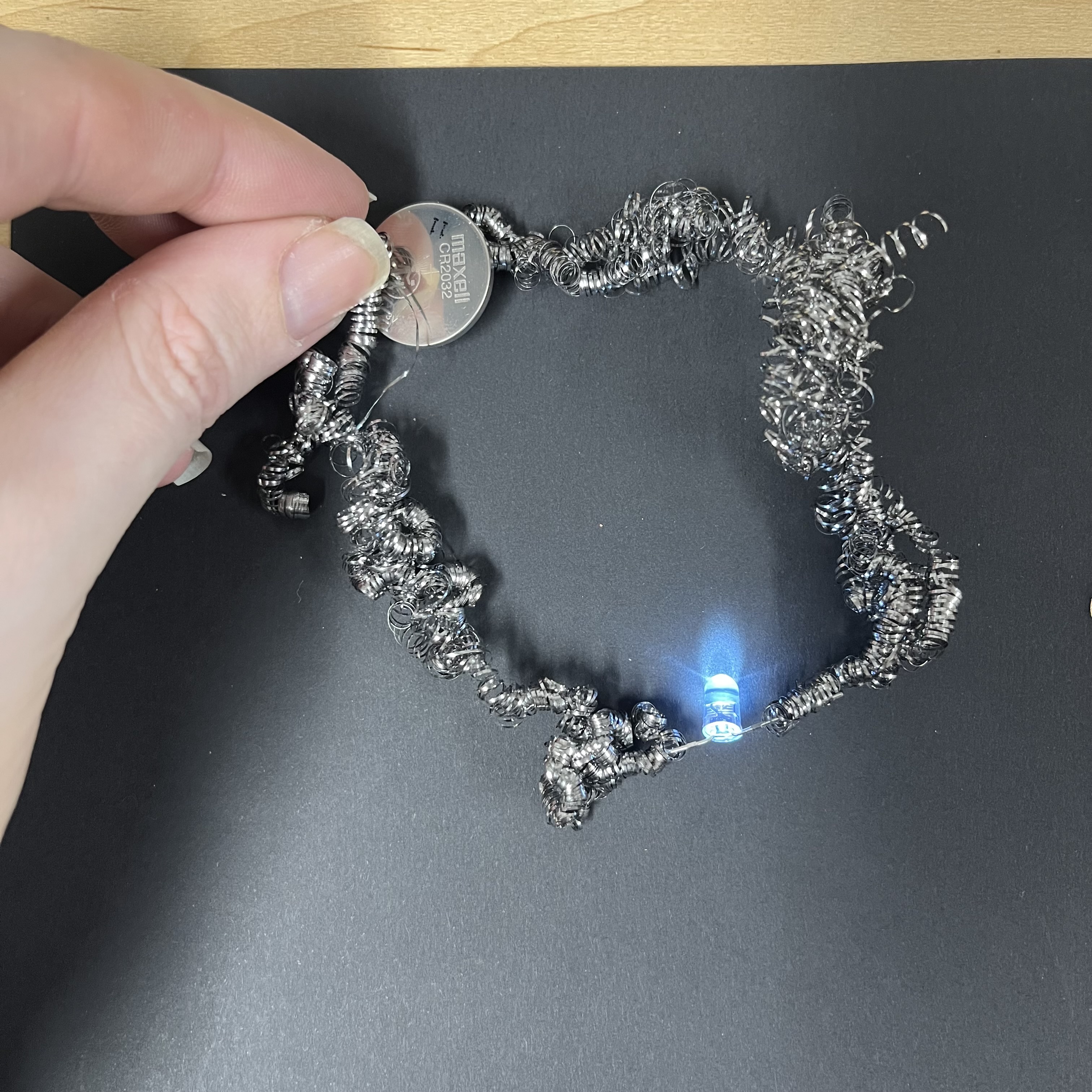 For my final circuit I used a steel coil scrubber and unwound it a bit. This was very finicky because the steel coil doesn't lay flat so the battery slides off of it. I had to squish the battery into it, and then use my thumb to press the steel coil into it on the other side to make enough contact to light the LED.